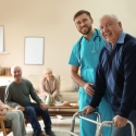 Care worker helping elderly man with walker